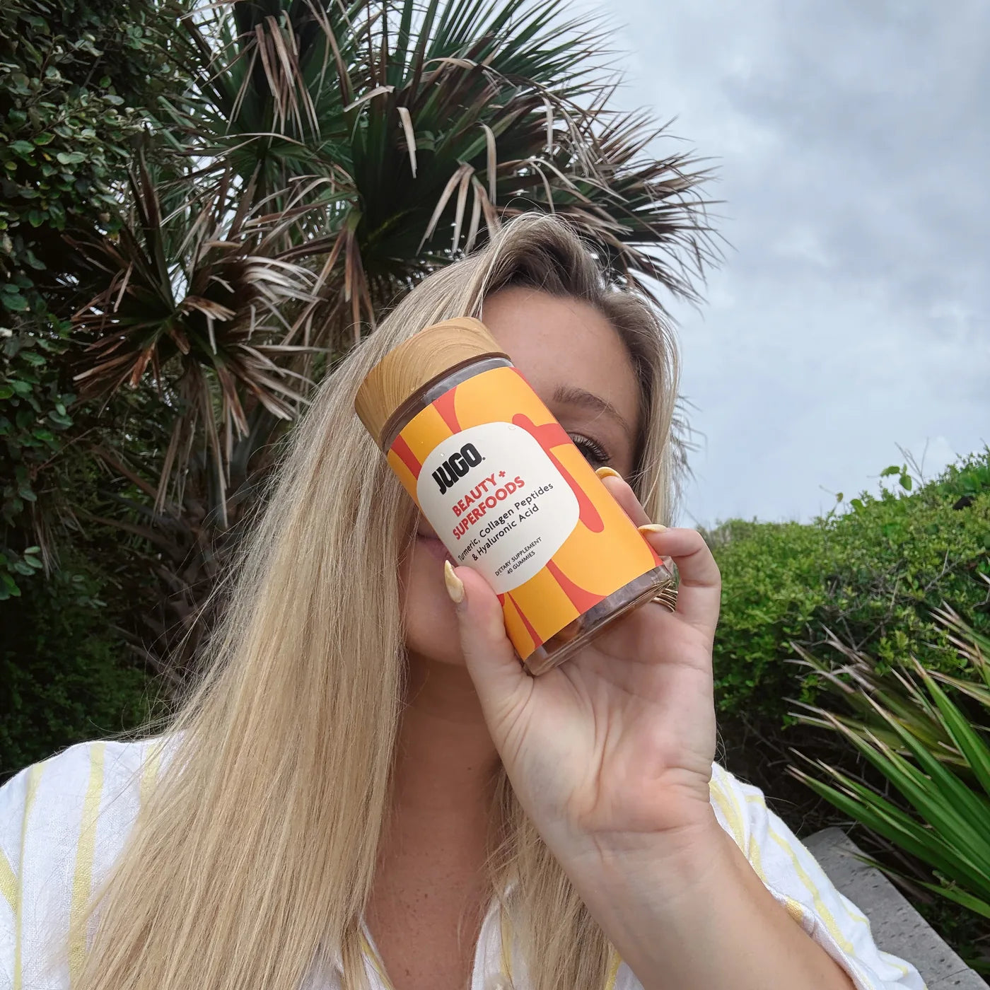 A JUGO Beauty + Superfoods fan holding the jar in the sun