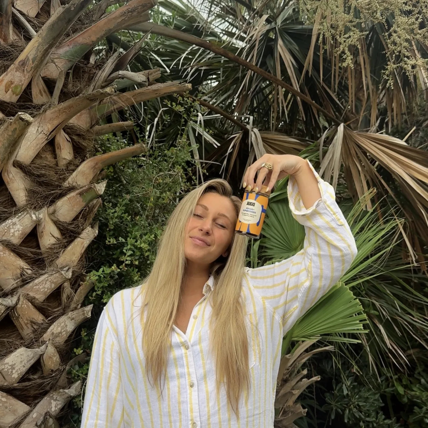 A JUGO Focus + Superfoods fan holding the jar outdoors